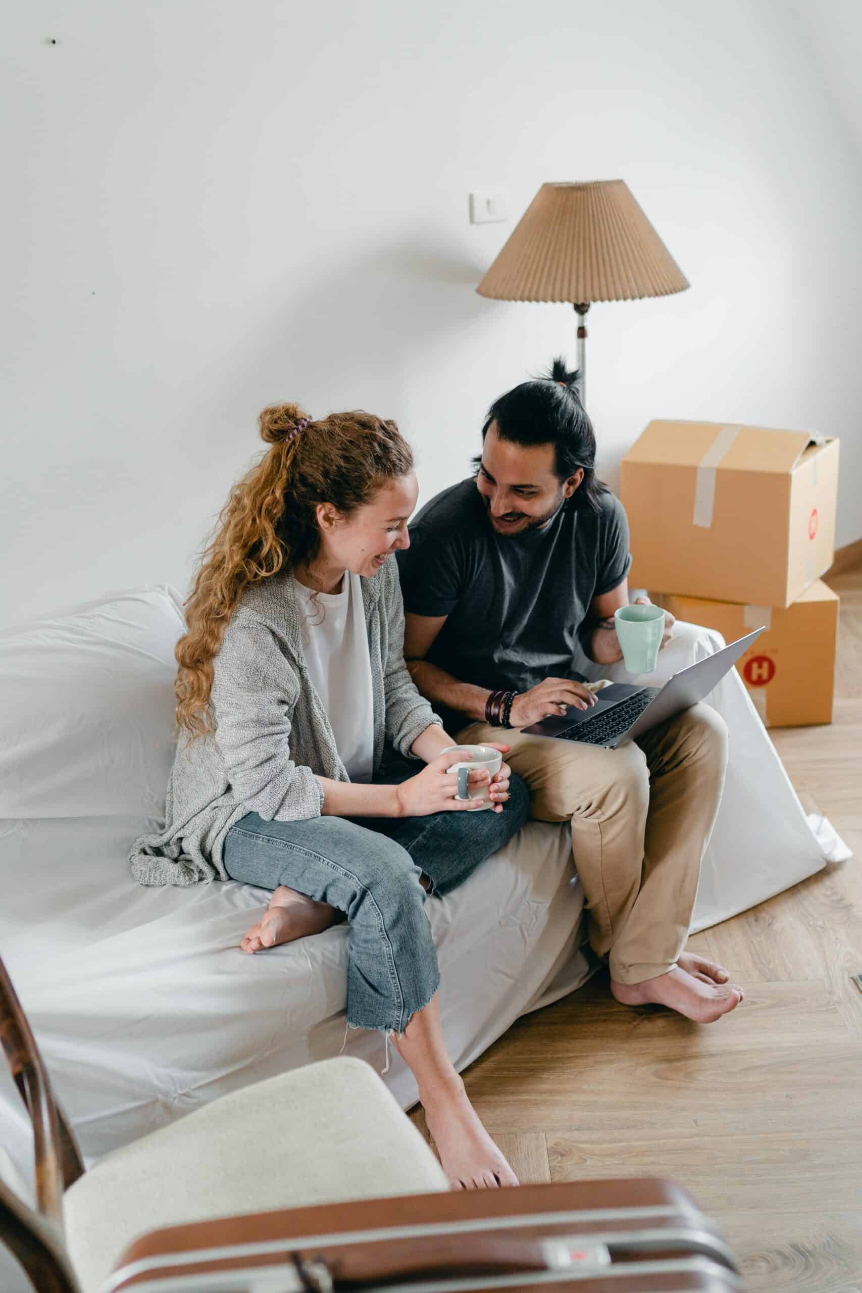 Man en vrouw die net in een nieuw huis zijn gaan wonen die kijken naar een laptop
